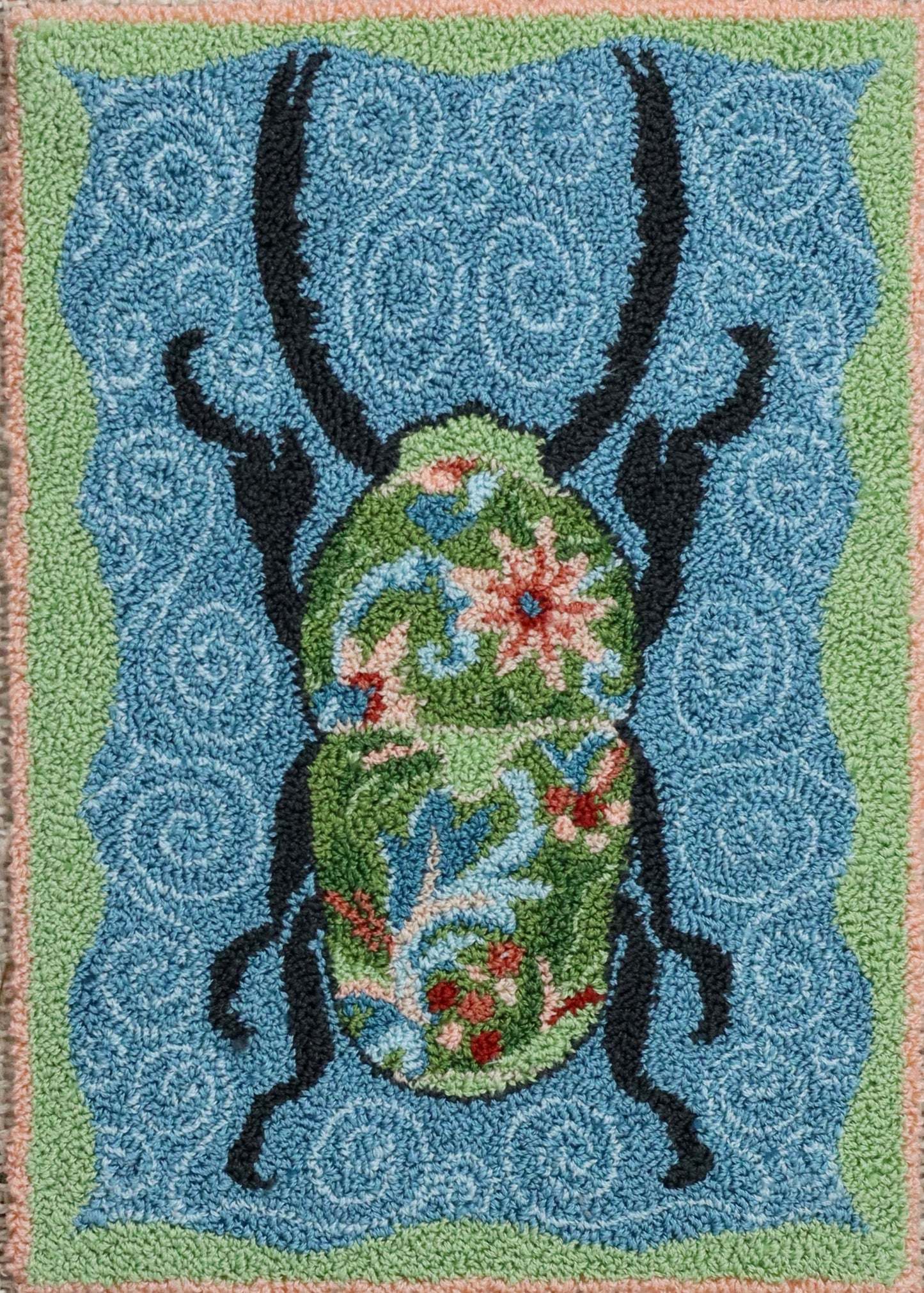 Decorative Punch Needle Pattern with a floral beetle design on a blue background by Orphaned Wool