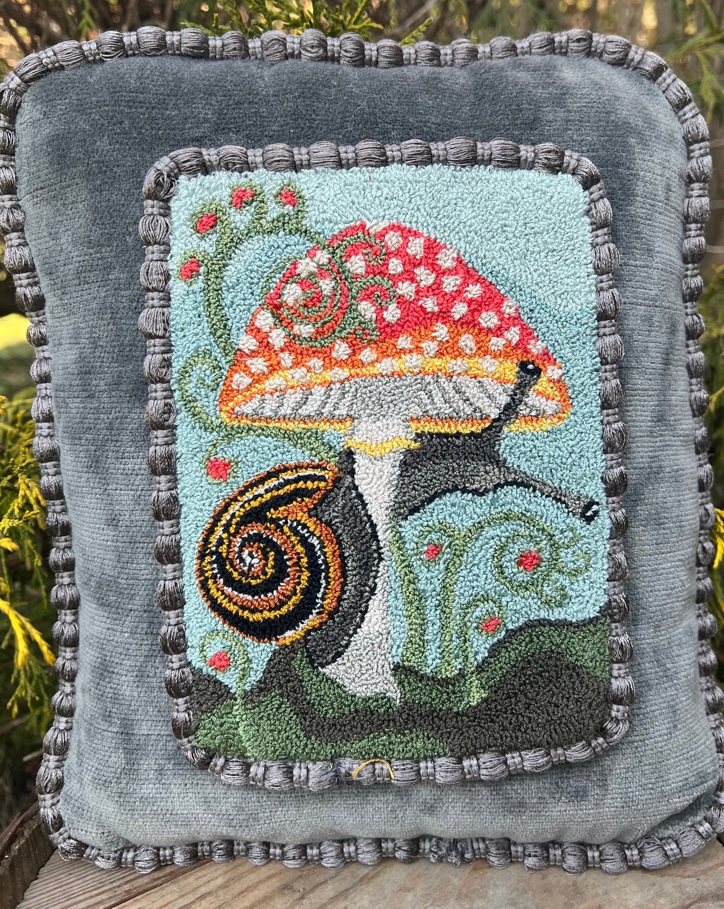The Pattern Entwined is a punch Needle Embroidery pattern that used thread and a punch needle to create the design. Entwinted design depicts a snail wrapping itself around a colorful mushroom. Copyright © 2024 Kelly Kanyok of Orphaned Wool.