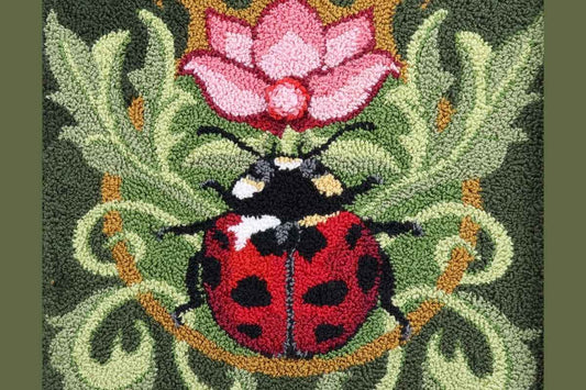 Close-up of punch needle loops on a ladybug design by Orphaned Wool showing textured loop formation and details.