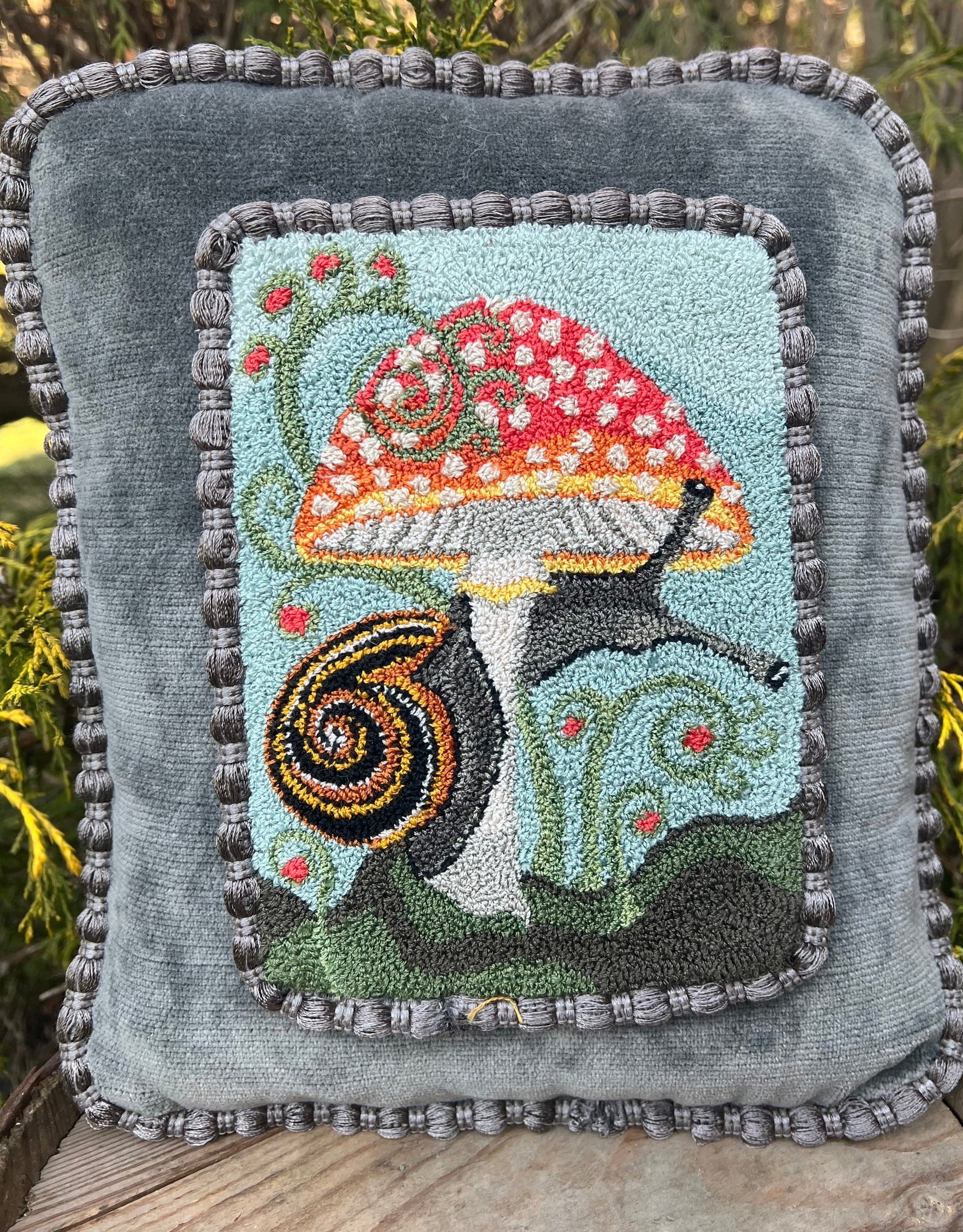 The Pattern Entwined is an PDF digial downloadable punch Needle Embroidery pattern that used thread and a punch needle to create the design. Entwined design depicts a snail wrapping itself around a colorful mushroom. Copyright © 2024 Kelly Kanyok of Orphaned Wool.