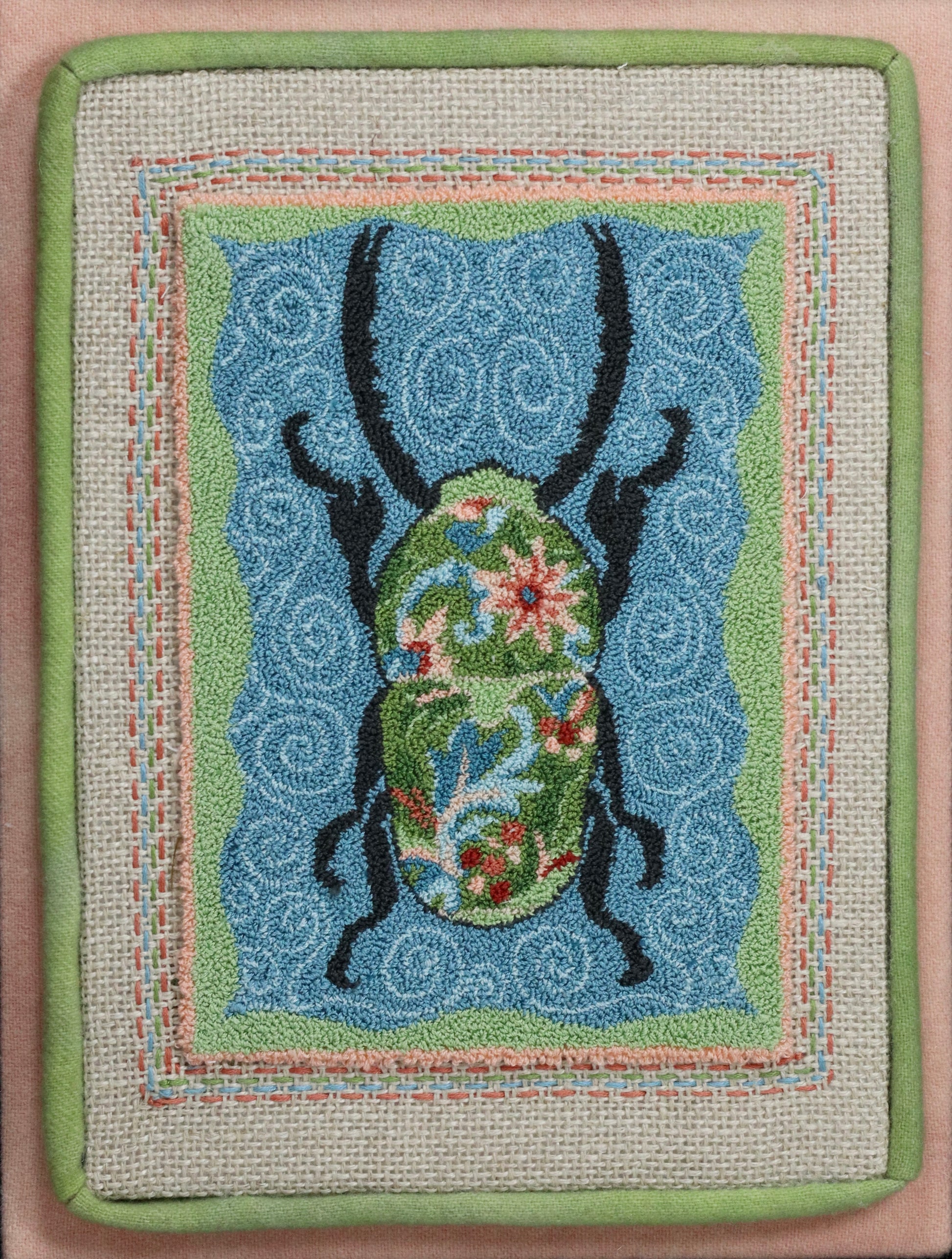 Punch Needle Embroidery artwork of a beetle with a floral design on a blue background, framed in black.