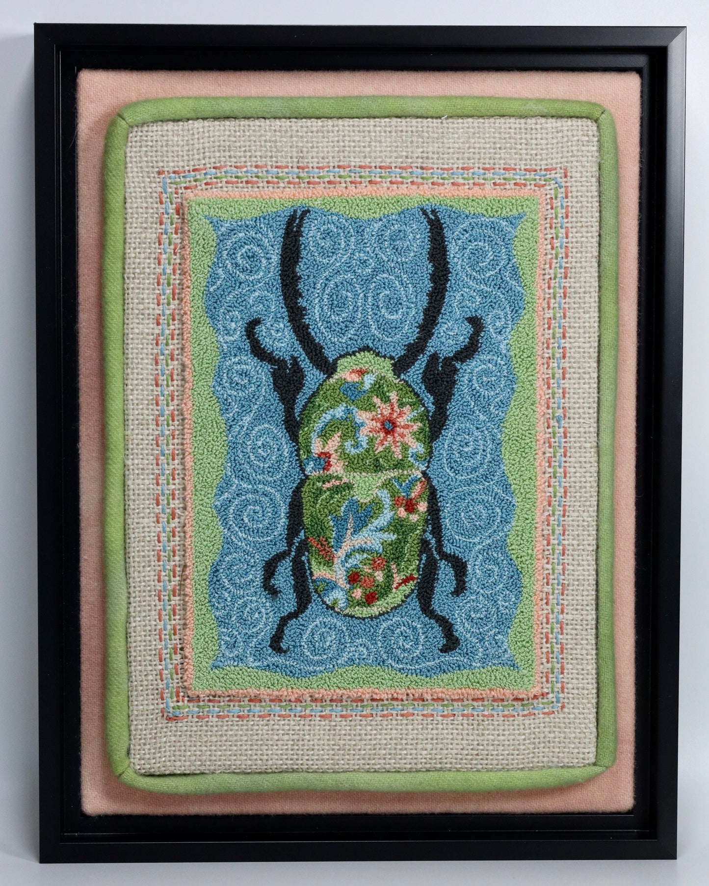 Punch Needle Embroidery artwork of a beetle with a floral design on a blue background, framed in black.