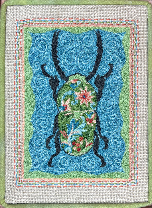 Decorative Punch Needle Pattern with a floral beetle design on a blue background by Orphaned Wool