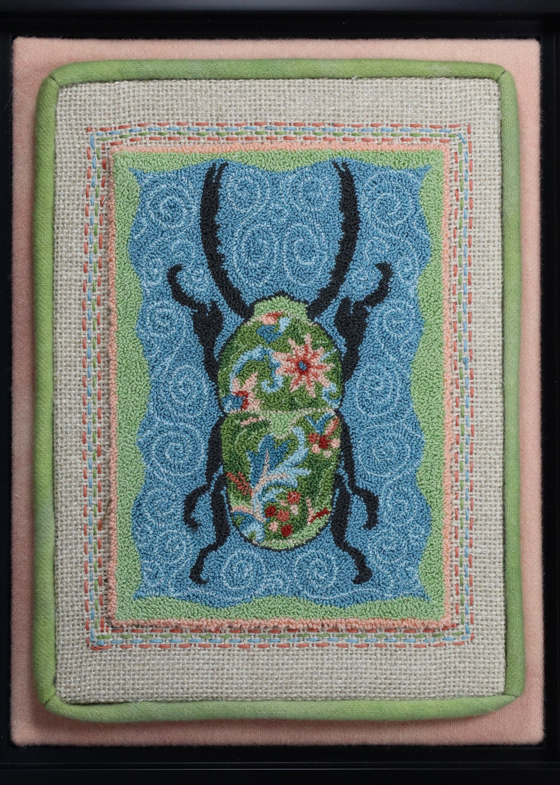 Punch Needle Embroidery artwork of a beetle with a floral design on a blue background, framed in black.