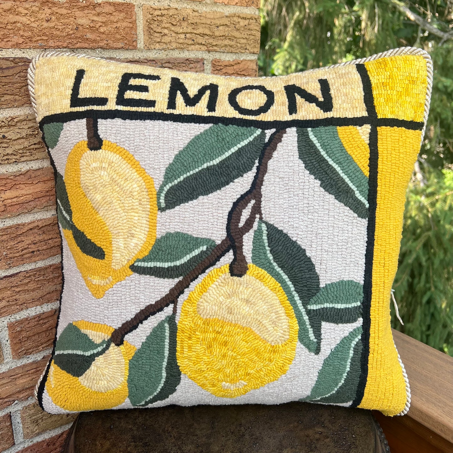 Lemon rug hooking pattern by Orphaned Wool, copyright © 2025 Kelly Kanyok.  This picture shows the finished design enlarged 300% to create a beautiful pillow. The design features three lemons with the word "lemon" on top.