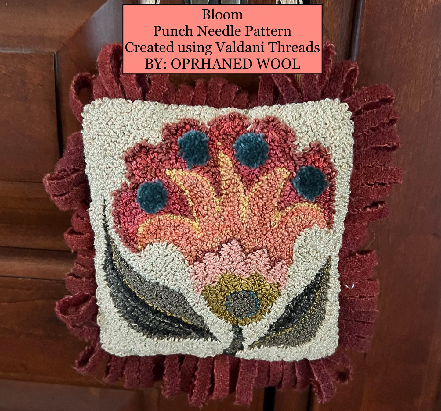 Punch needle pattern with floral design on a wooden surface, featuring Valdani Threads.